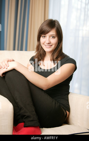 Mädchen (17) mit roten Socken auf Sofa sitzen, Lächeln Stockfoto