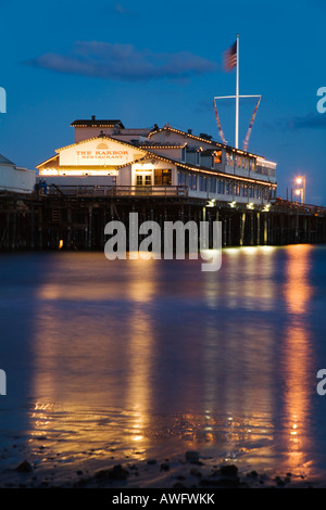 CALIFORNIA Santa Barbara Stearns Wharf Pier erstrecken sich in pazifischen Ozean Hafenrestaurant Gebäude bei Abenddämmerung Gebäude und Flagge Stockfoto