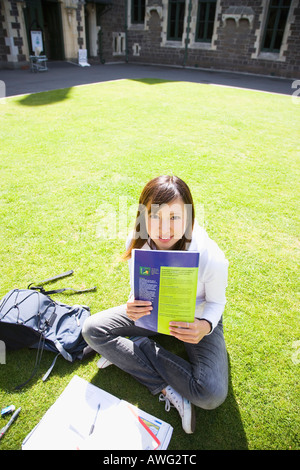 Junge Frau sitzt auf Rasen Stockfoto