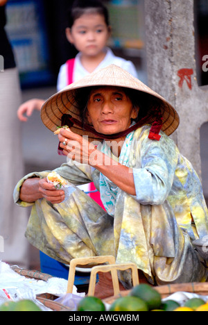 Asien Fernost Vietnam Hoi an Markt alte Dame Straße Verkäufer konischen Hut nicht bai tho Verkauf von grünen Mandarinen Pausen für Snack Stockfoto