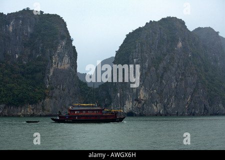 Ein zwei Masten JUNK sitzt ruhig unter den steilen Klippen von Kalkstein Inseln HALONG Bucht VIETNAM Stockfoto