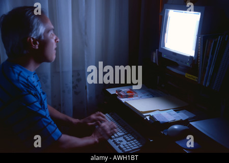 Ein Mann mittleren Alters arbeiten am Computer in seinem Büro zu Hause in SLC, Utah, USA. Bewegung & Transparenz zeigt sich aufgrund der langen messen. Stockfoto