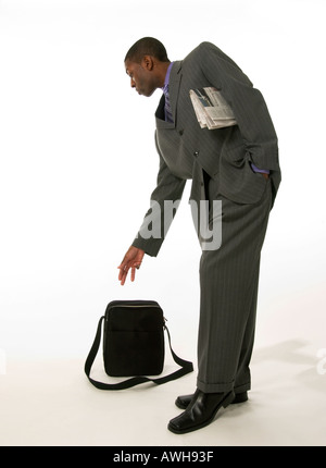 Geschäftsmann, der Zeitung unter dem Arm trägt, während er nach Tasche greift, USA Stockfoto
