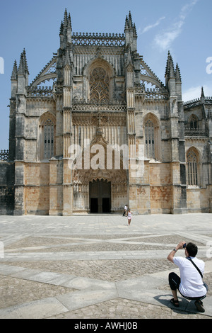 Ein Mann nimmt ein Snapshot-Foto von seiner Frau vor dem prunkvollen Kloster Batalha Portugal. Stockfoto