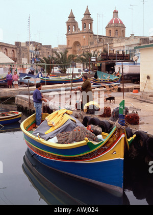 Ein Fischer, der Netze am Hafen im maltesischen Hafen Marsaxlokk sortiert Stockfoto