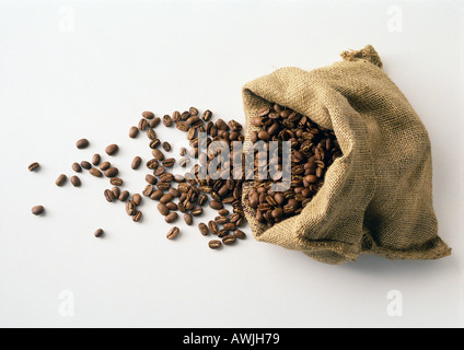 Kaffeebohnen in und aus Leinensack verschütten Stockfoto