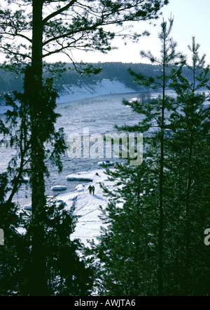 Schweden, immergrüne Bäume und Menschen zu Fuß auf verschneiten Ufer in Ferne Stockfoto