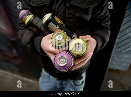 Graffiti-Künstler mit Maske malt spray ein Wandbild an der Wand Stockfoto