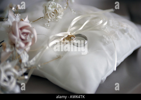 Ein Porträt von einer Braut und Bräutigam Hochzeit Ringe gesehen hier auf einem weißen Kissen umgeben von einem Blumenstrauß Stockfoto