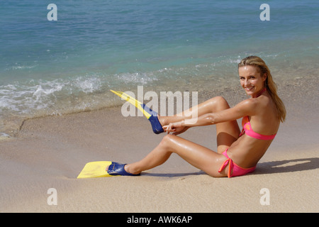 Frau in rosa Bikini saß an einem Strand auf gelben flossen Stockfoto