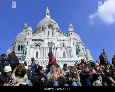 Touristen sitzen auf den Stufen zur Basilika Sacre Coeur in Paris Stockfoto