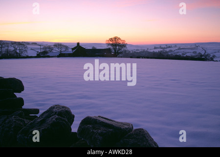 Lila Himmel der Dämmerung über Schnee bedeckt Felder von einem Bergbauernhof Stockfoto