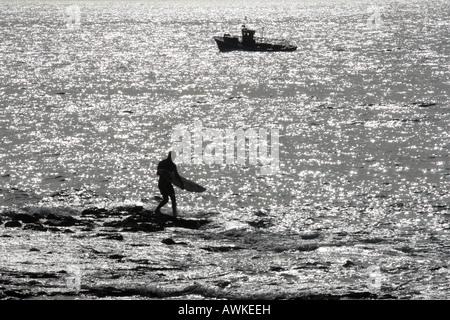 Junge Surfer aufbrechen, um Meer und Angelboot/Fischerboot im Punta Blanca in der Nähe von Alcala Teneriffa Kanarische Inseln Spanien Stockfoto