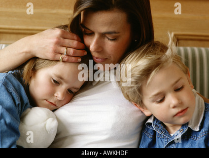 Frau zwischen zwei Kindern, hielt des kleinen Mädchens Kopf an ihre Brust, kleiner Junge gelehnt, Nahaufnahme Stockfoto