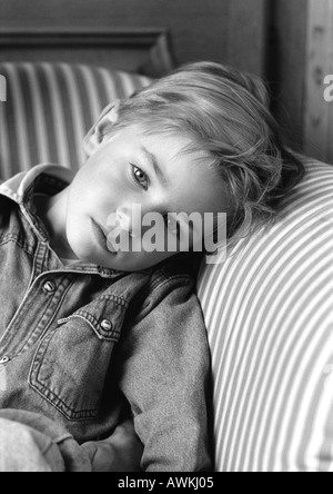 Kleiner Junge schiefen Kopf auf Stuhl Arm, schwarz / weiß Porträt. Stockfoto