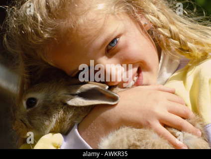 Mädchen umarmt Kaninchen, close-up Stockfoto