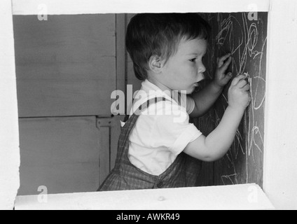 Kleiner Junge Schrift an Wand, Seitenansicht, b&w Stockfoto