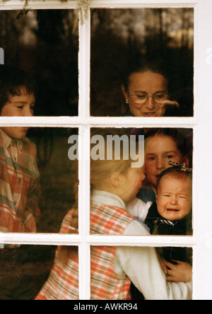 Reife Frau und Kinder hinter Fenster Stockfoto