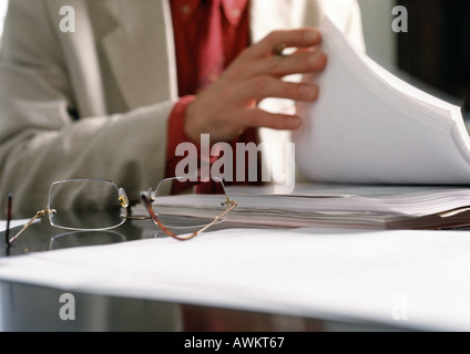 Mann tut Papierkram, Fokus auf Brillen auf Schreibtisch Stockfoto