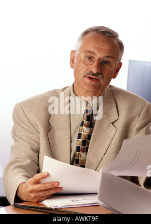 Mann am Schreibtisch sitzt, hält Dokument Stockfoto