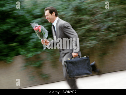 Geschäftsmann hält Aktenkoffer und Blumenstrauß, laufen, unscharf Stockfoto