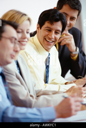 Geschäftsleute, die nebeneinander sitzen an einem Tisch, Lächeln Stockfoto