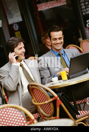 Zwei Geschäftsleute sitzen im Café-Terrasse, mit Handy und Laptop-computer Stockfoto