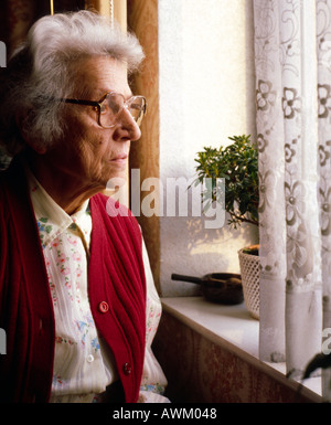 Ältere Frau, die durch Fenster Stockfoto