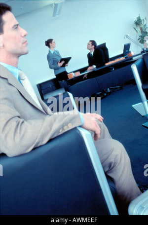Seitenansicht der Geschäftsmann im Sessel sitzen mit zwei Geschäftsleute im Hintergrund Stockfoto