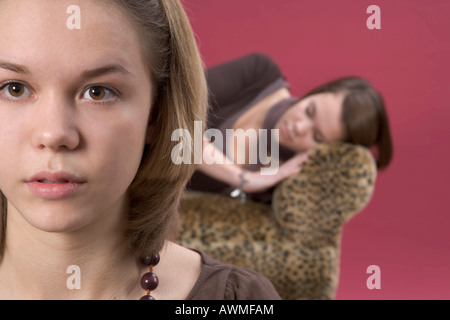 Zwei Mädchen, Pre-Teens, Teenager, man schläft auf einem Tiger-Print-Sofa mit den anderen im Vordergrund Stockfoto