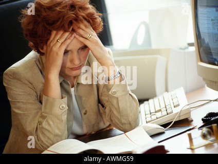 Geschäftsfrau sitzen am Schreibtisch, die Hände auf den Kopf Stockfoto