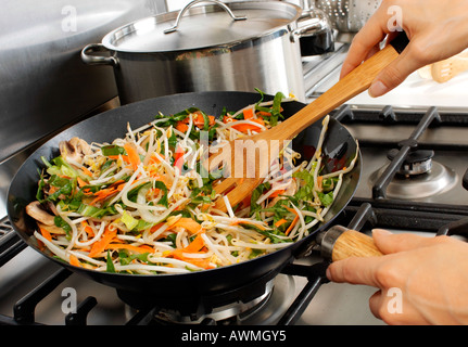 FRAU IN DER KÜCHE PFANNE BRATEN GEMÜSE Stockfoto