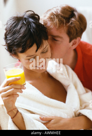 Mann küsst Frau von hinten, Frau mit Glas Saft, Kopf und Schultern, close-up Stockfoto