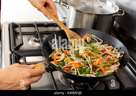 FRAU IN DER KÜCHE PFANNE BRATEN GEMÜSE Stockfoto