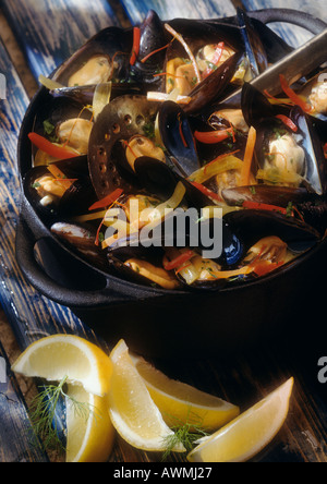 Muscheln in Weißwein in Topf mit Zitronenspalten auf der Seite, Nahaufnahme Stockfoto