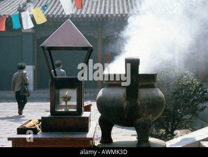 China, Provinz Hebei, Beijing, Räuchergefäß ablassen Rauch im Innenhof, Menschen im Hintergrund Stockfoto