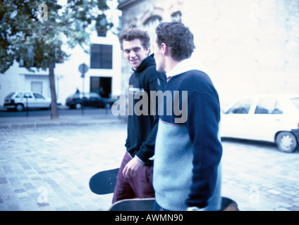Zwei junge Männer auf Straße, skateboards holding Stockfoto