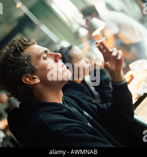Junger Mann rauchte eine Zigarette, Seitenansicht Stockfoto