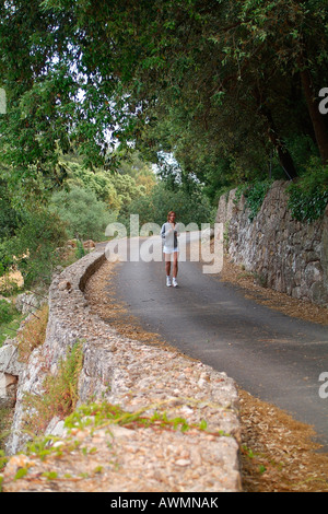 Junge Frau in Sportkleidung läuft auf einem Waldweg Stockfoto