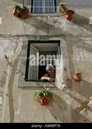 Eine Frau hängt Wäsche zum Trocknen vor ihrem zweiten Geschichtefenster in Sintra Portugal Stockfoto