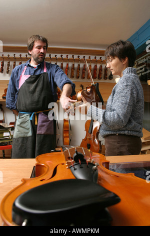 Geigenbauer (Geigenbauer) mit einem Kunden in seinem Geschäft Stockfoto