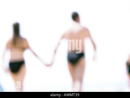 Mann und Frau, die Hand in Hand am Strand, Rückansicht, in Ferne unscharf. Stockfoto