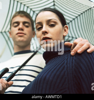 Junger Mann und junge Frau unter Dach außerhalb des Mannes Hand auf Frau Schulter Stockfoto