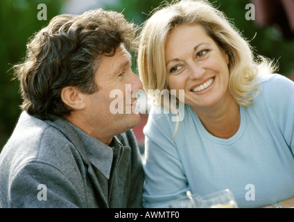 Mann und Frau sitzen dicht beieinander, lächelnd, Nahaufnahme Stockfoto