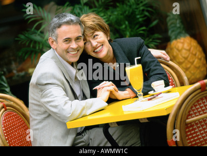 Mann und Frau sitzen am Tisch gelehnt nahe beieinander, Porträt Stockfoto