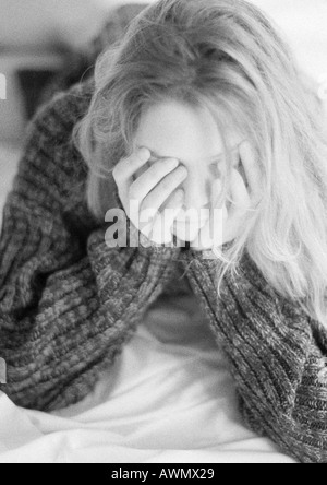Frau liegt auf dem Bett, stützte sich auf Ellenbogen, Hände über Gesicht, schwarz / weiß Stockfoto