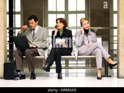 Unternehmerinnen mit Handys sitzt neben Geschäftsmann mit Laptop-Computer. Stockfoto