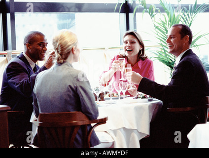 Gruppe von Geschäftsleuten zusammen am Tisch sitzen, Lächeln und Erhöhung der Gläser. Stockfoto