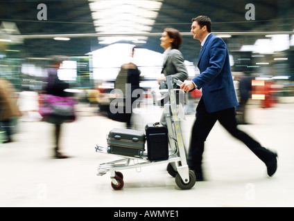 Unternehmer und Unternehmerin zu Fuß mit Gepäck Durchgangsbahnhof, verwischt. Stockfoto