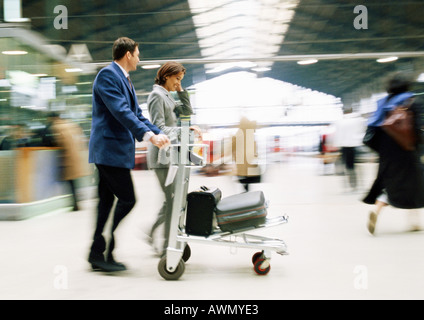Unternehmer und Unternehmerin zu Fuß mit Gepäck Durchgangsbahnhof, verwischt. Stockfoto